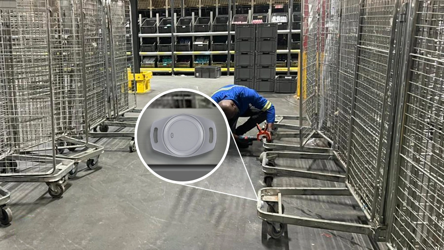 Travailleur installation de la balise de suivi des actifs M2 BLE sur un chariot d'entrepôt en métal dans une installation de stockage industrielle avec des étagères