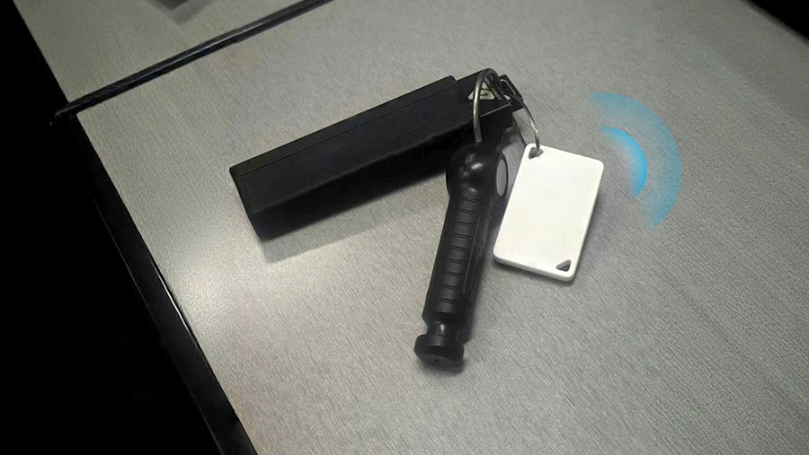 M4 LITE Bluetooth Etiqueta conectada a una unidad de pulgar USB segura sobre la superficie de un escritorio